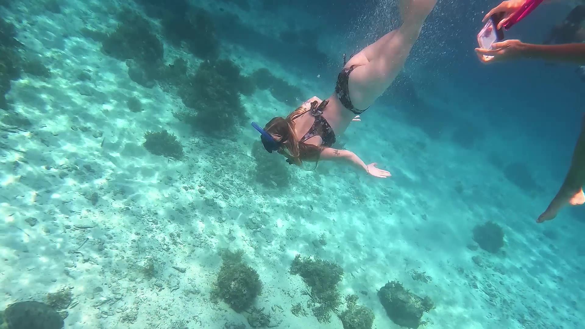 Snorkelers swimming over a shallow reef in clear turquoise water, Palawan